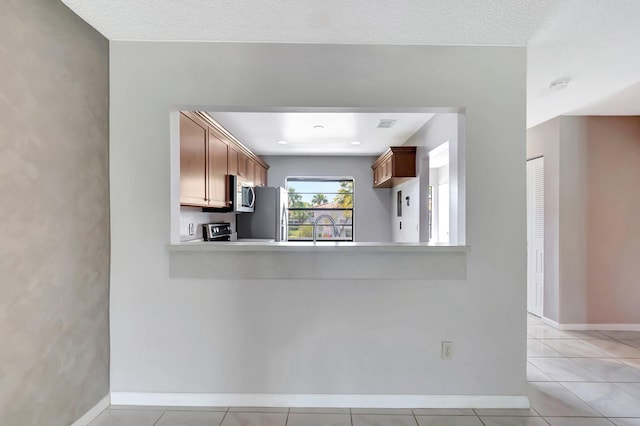 kitchen featuring light tile patterned flooring, a sink, baseboards, light countertops, and stainless steel microwave