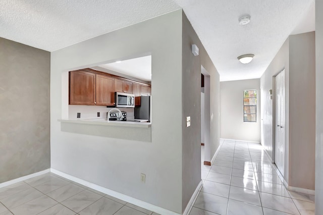 interior space with a textured ceiling, baseboards, and light tile patterned floors