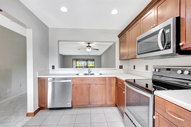 kitchen with light tile patterned floors, light countertops, appliances with stainless steel finishes, and a sink