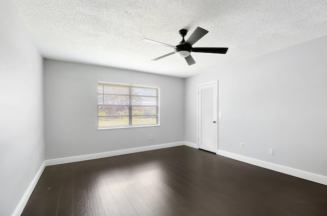 spare room with dark wood-style floors, a textured ceiling, a ceiling fan, and baseboards