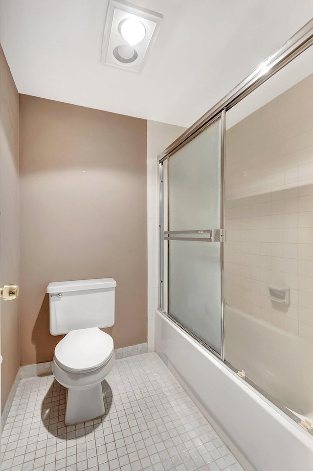 bathroom featuring combined bath / shower with glass door, tile patterned flooring, toilet, and baseboards