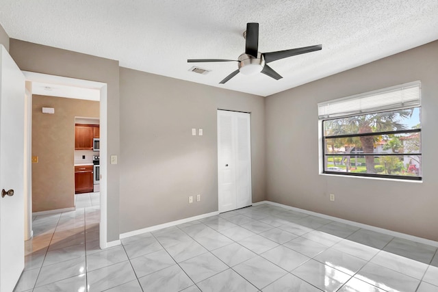 unfurnished bedroom featuring a closet, visible vents, a ceiling fan, a textured ceiling, and baseboards