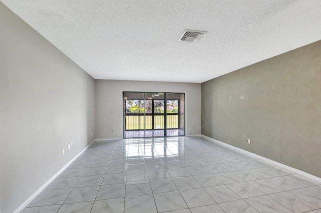 spare room featuring light tile patterned floors, baseboards, visible vents, and a textured ceiling