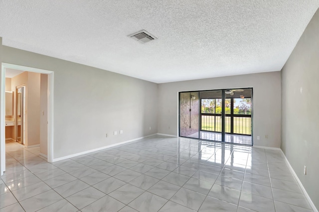 unfurnished room featuring visible vents, a textured ceiling, baseboards, and light tile patterned flooring