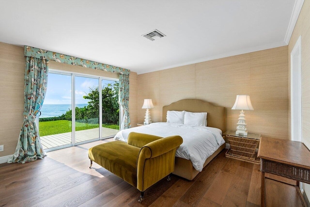 bedroom featuring access to exterior, a water view, hardwood / wood-style floors, and ornamental molding