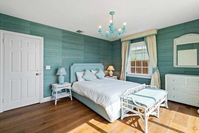 bedroom with hardwood / wood-style floors and a notable chandelier