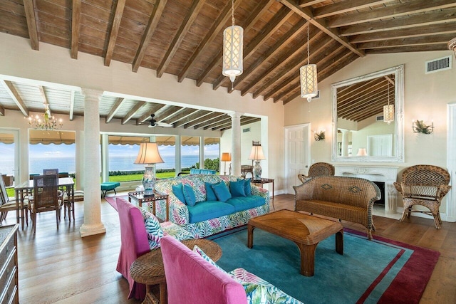 living room with a water view, beam ceiling, hardwood / wood-style flooring, and ornate columns