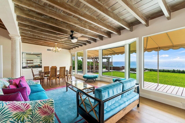 sunroom with beam ceiling, wooden ceiling, a water view, ceiling fan with notable chandelier, and ornate columns