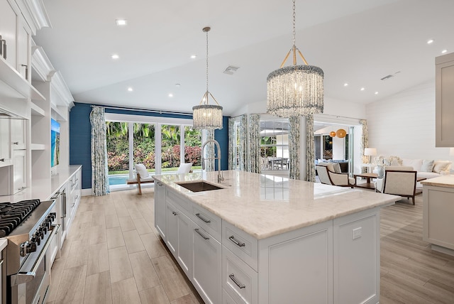 kitchen featuring lofted ceiling, a center island with sink, hanging light fixtures, and sink