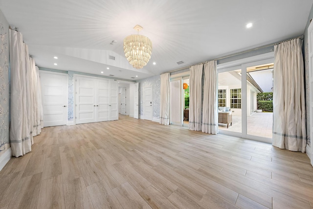 unfurnished living room with an inviting chandelier, lofted ceiling, and light hardwood / wood-style floors