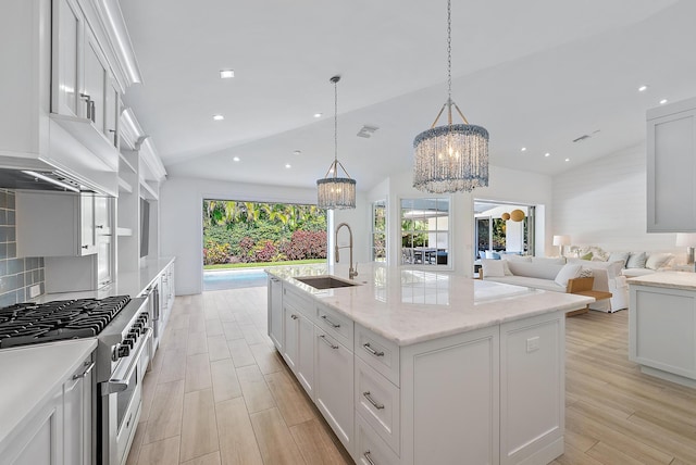 189 Shelter Ln, Jupiter Inlet Colony, FL 33469 - kitchen with stainless steel stove, vaulted ceiling, a chandelier, light wood-type flooring, and a center island with sink