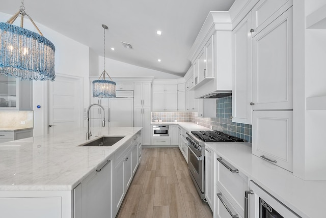 189 Shelter Ln, Jupiter Inlet Colony, FL 33469 - kitchen with premium appliances, lofted ceiling, tasteful backsplash, white cabinetry, and a large island with sink
