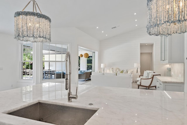 189 Shelter Ln, Jupiter Inlet Colony, FL 33469 - kitchen featuring a chandelier, light stone counters, high vaulted ceiling, open floor plan, and decorative light fixtures