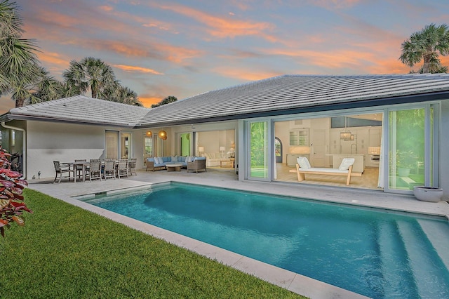 189 Shelter Ln, Jupiter Inlet Colony, FL 33469 - back of property at dusk with an outdoor pool, stucco siding, a patio, an outdoor living space, and a lawn