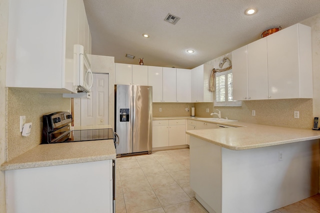 kitchen with kitchen peninsula, sink, light tile patterned floors, appliances with stainless steel finishes, and white cabinets