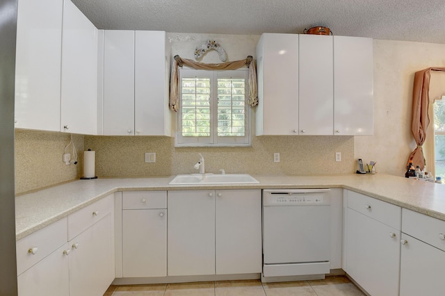 kitchen with white dishwasher, sink, and white cabinets