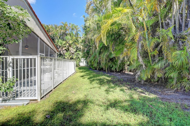 view of yard featuring ceiling fan and a sunroom