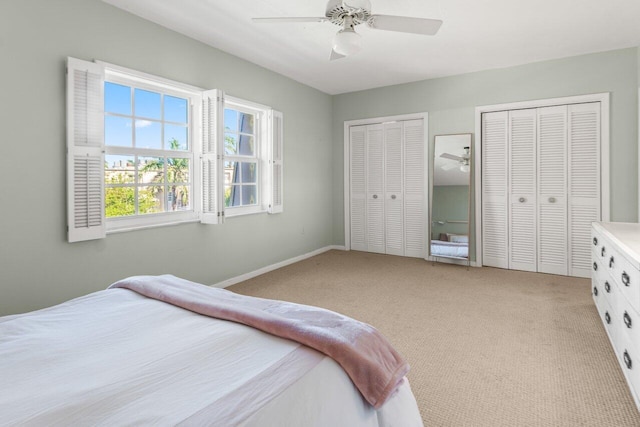 bedroom with ceiling fan, light colored carpet, and multiple closets