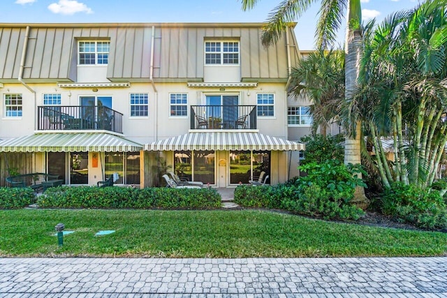 view of front facade with a balcony and a front lawn