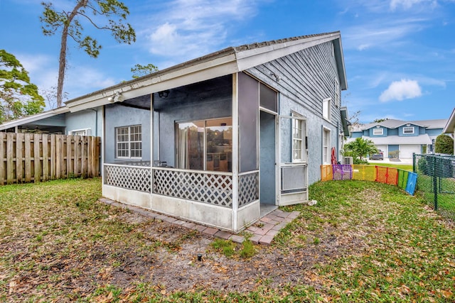 rear view of house with a lawn and a sunroom