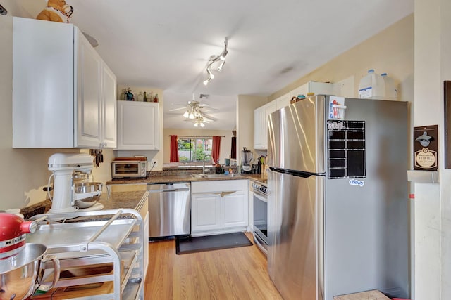 kitchen with ceiling fan, sink, light wood-type flooring, appliances with stainless steel finishes, and white cabinets