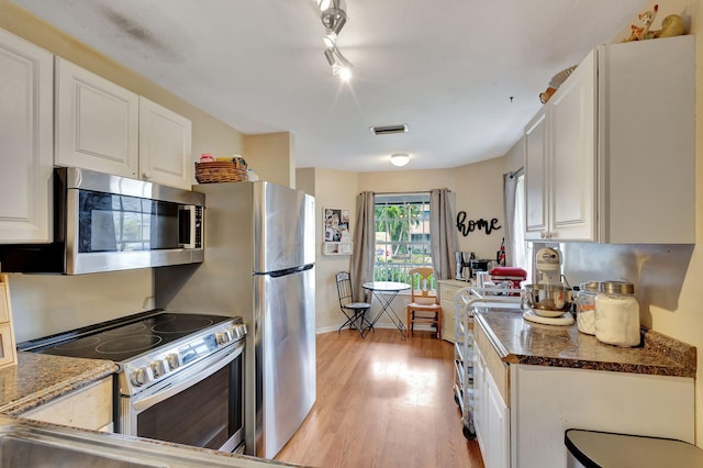 kitchen featuring light hardwood / wood-style flooring, track lighting, stainless steel appliances, and white cabinetry