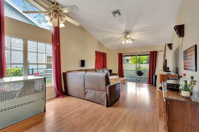 living room with light hardwood / wood-style floors, plenty of natural light, lofted ceiling with skylight, and ceiling fan