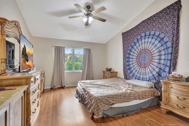 bedroom with ceiling fan, a textured ceiling, light hardwood / wood-style flooring, and vaulted ceiling