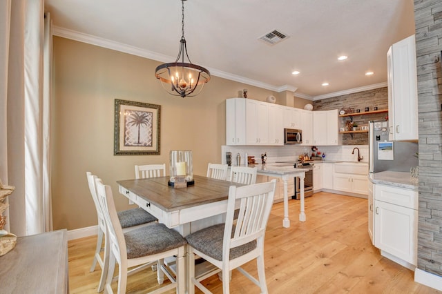 dining area with an inviting chandelier, crown molding, and light hardwood / wood-style floors