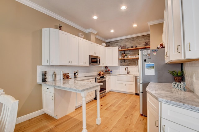 kitchen with white cabinetry, light hardwood / wood-style flooring, ornamental molding, appliances with stainless steel finishes, and light stone countertops