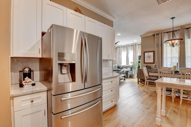 kitchen featuring tasteful backsplash, light stone counters, stainless steel fridge, and white cabinets