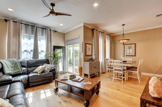 living room with crown molding, ceiling fan with notable chandelier, and light hardwood / wood-style floors