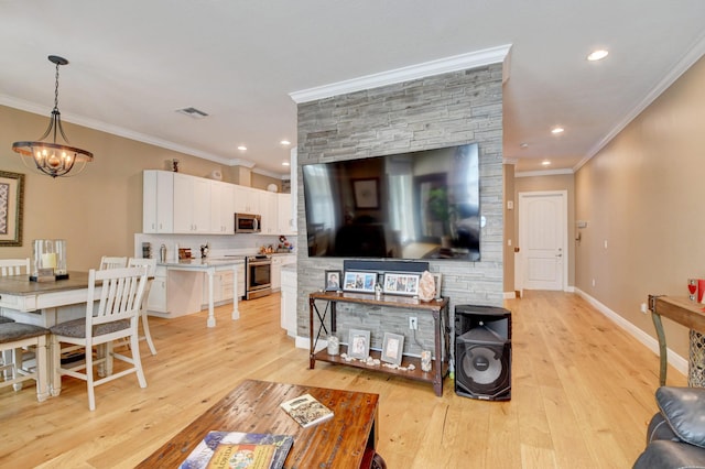 living room with ornamental molding, a notable chandelier, and light hardwood / wood-style flooring