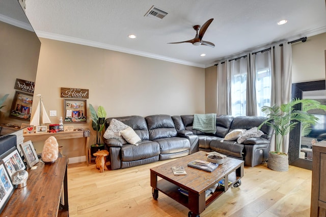 living room featuring crown molding, ceiling fan, a textured ceiling, and light wood-type flooring