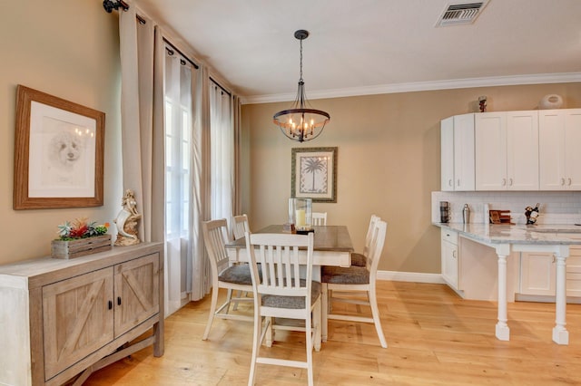 dining space featuring ornamental molding, light hardwood / wood-style floors, and a chandelier