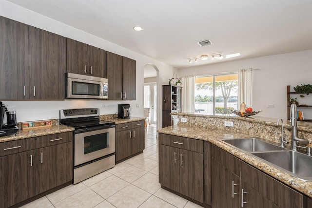 kitchen with light tile patterned floors, sink, stainless steel appliances, and dark brown cabinetry