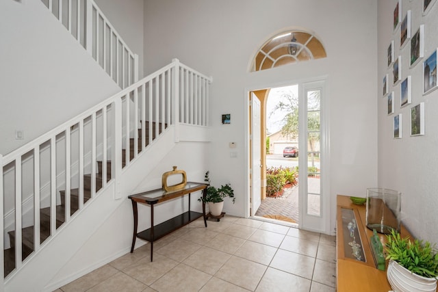 entryway with a towering ceiling and light tile patterned flooring