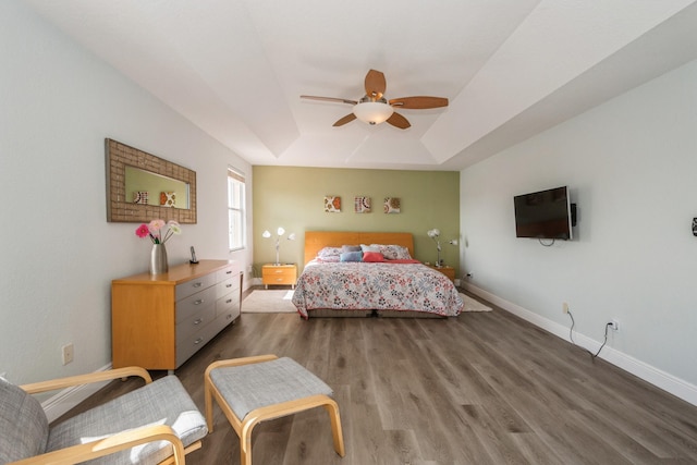 bedroom featuring a raised ceiling, ceiling fan, and dark hardwood / wood-style floors