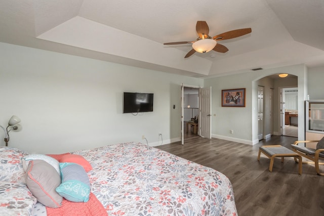 bedroom featuring ceiling fan, a tray ceiling, and dark hardwood / wood-style flooring