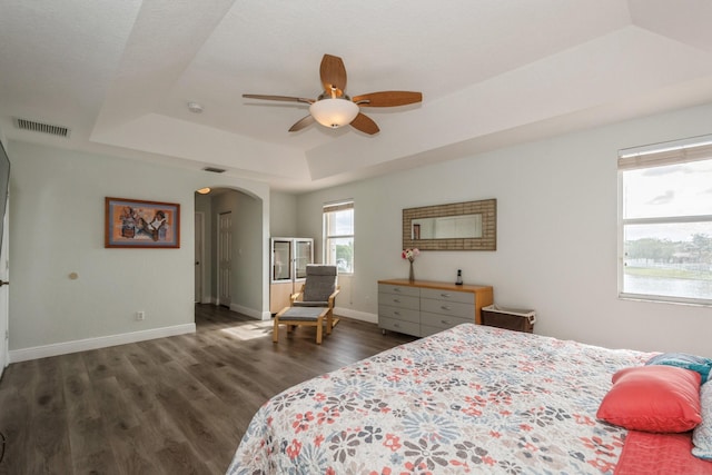 bedroom with a raised ceiling, ceiling fan, and dark hardwood / wood-style flooring