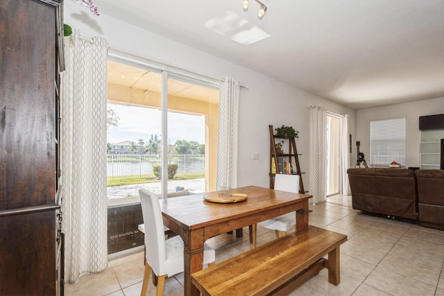 dining area featuring a water view and light tile patterned flooring