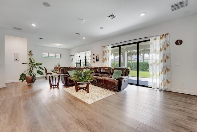 living room featuring a wealth of natural light, visible vents, and wood finished floors