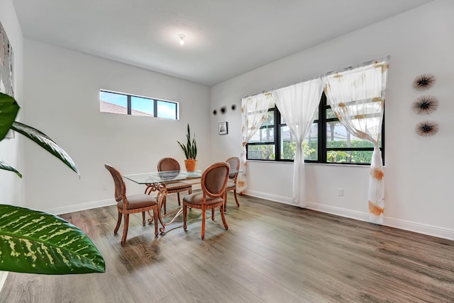 dining space featuring plenty of natural light, wood finished floors, and baseboards