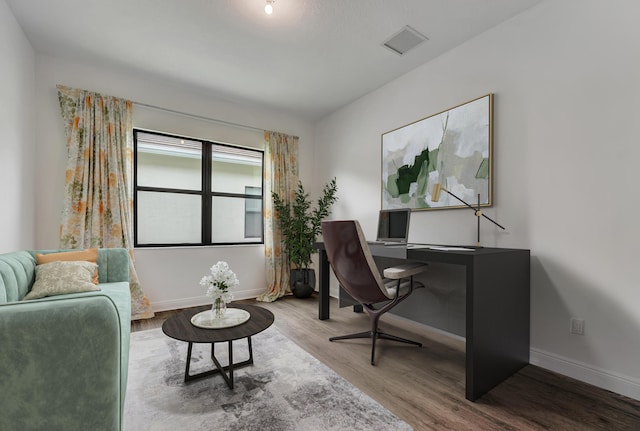 office area featuring visible vents, baseboards, and wood finished floors