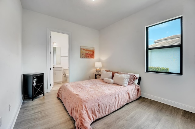 bedroom with light wood-type flooring, connected bathroom, and baseboards