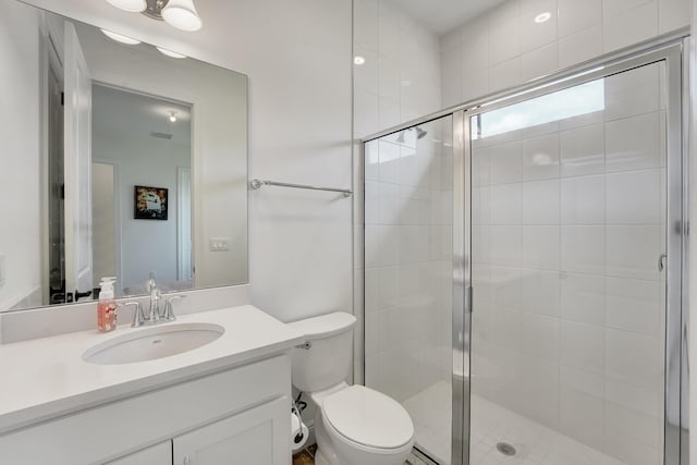 bathroom with an enclosed shower, vanity, and toilet