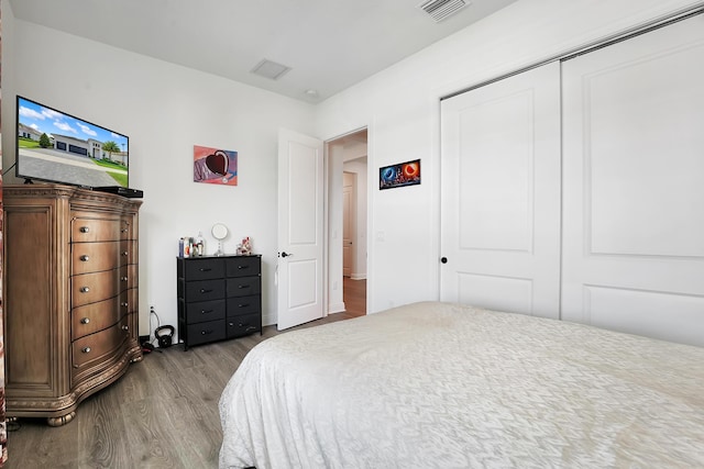 bedroom with a closet, visible vents, and wood finished floors