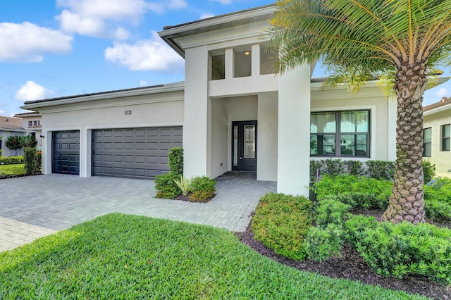 view of front facade featuring a garage, decorative driveway, and stucco siding