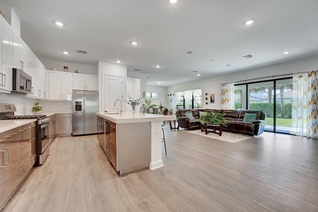 kitchen featuring visible vents, light wood-style flooring, appliances with stainless steel finishes, open floor plan, and a sink