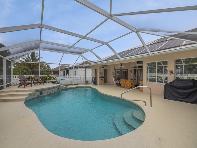 view of pool with a lanai, a patio, pool water feature, area for grilling, and ceiling fan